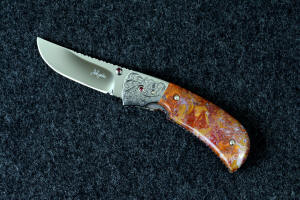 "Bellatrix" custom folding knife, obverse side view in T3 deep cryogenically treated ATS-34 high molybdenum martensitic stainless steel blade, hand-engraved 304 stainless steel bolsters, differerentially anodized 6AL4V titanium liners, Roostertail Agate gemstone handle, 304 stainless steel fasteners with garnet faceted gemstones