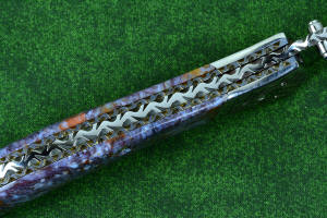 Macro enlargement of "Starling" fine handmade custom folding knife, liner and blade filework detail. Note differentially anodized blue and gold titanium liners and full fine filework throughout