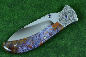 Macro enlargement of "Starling" fine handmade custom folding knife, obverse side view in high molybdenum stainless steel blade, engraved stainless bolsters, faceted amethyst gemstone accents and Rio Grande Agate handle